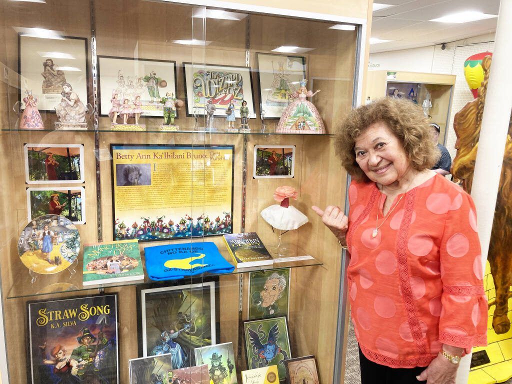 Betty Ann Bruno points to a display featuring her work and appearance in the film The Wizard of Oz at the Oz Stravaganza 2023 in Chittenango New York - Thrill NG